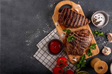 Ahşap kesme tahtasında ızgara biftek, ketçap sosu ve baharat, üst görünüm kopya alanı.