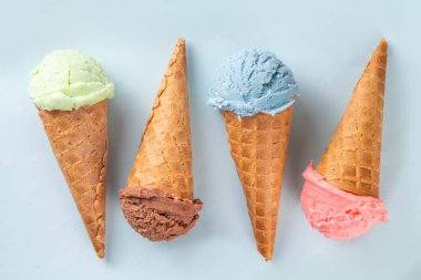  Parlak arka planda waffle külahlı renkli parlak dondurma. Taze böğürtlenli farklı dondurma külahları üst görünüm fotokopi alanı arka planı