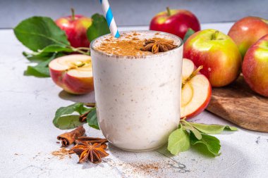 Apple pie smoothie with yogurt, apple slices, oatmeal granola flakes, cinnamon, spices and walnuts. Healthy uatumn breakfast or snack, with fresh raw apples and spices copy space