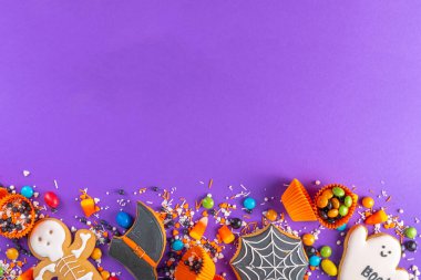 Bright colorful Halloween gingerbread cookies and sweet background. Homemade biscuits with cookie cutters, sugar sprinkles and candies. High-colored Halloween treats flat lay top view copy space clipart