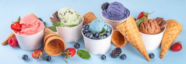 Renkli arka planda waffle konileri ve böğürtlenlerle dolu renkli, parlak dondurmalar. Taze böğürtlenli farklı aromalı dondurma porsiyonları üst görünüm kopya alanı arka planı