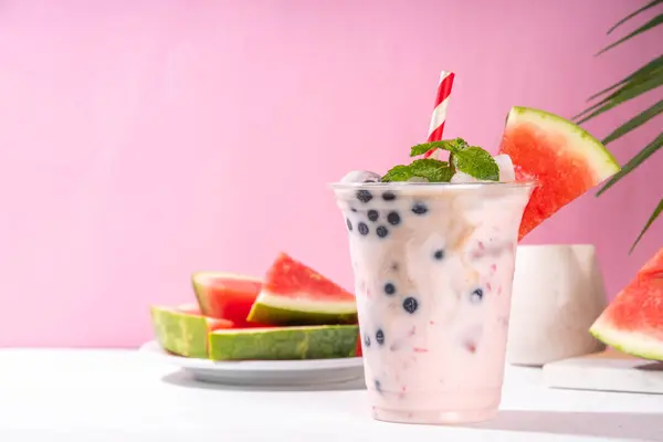 stock image Watermelon boba balls bubble tea cocktail. Refreshing milky non-dairy milkshake cocktail with boba balls and watermelon slices on background. Summer garnished sweet dessert iced drink 