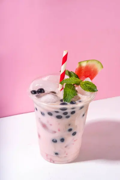 stock image Watermelon boba balls bubble tea cocktail. Refreshing milky non-dairy milkshake cocktail with boba balls and watermelon slices on background. Summer garnished sweet dessert iced drink 