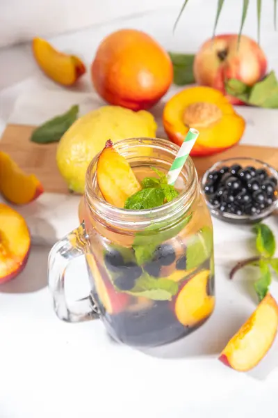 stock image Arnold Palmer Iced Tea with Boba balls or Tapioca pearls, Cold Peach Lemon Bubble Tea, colorful bubble lemonade in mason jar, with fresh fruits on white table background