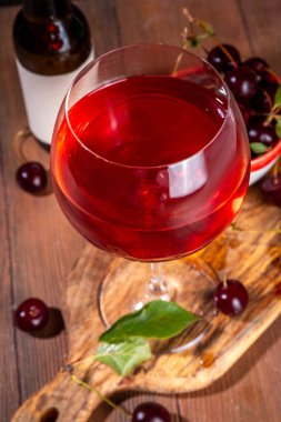 Tatlı alkollü kiraz şarabı, ev yapımı kiraz şarabı ya da taze kirazlı likör mutfak masasında fotokopi alanı.