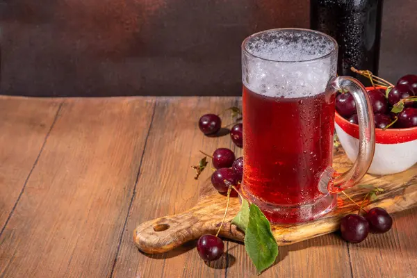 stock image Craft cherry beer or cider alcohol drink mug and bottle on wooden table with fresh ripe cherries, copy space