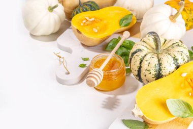 Bal kabakları değişik boyutlarda, çeşitli boyut ve renklerde kabaklar, bitki ve baharatlar, zeytin yağı, bal, beyaz mutfak masası arka planında üst görünümde fotokopi alanı 