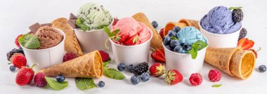 Beyaz arka planda waffle külahları ve böğürtlenlerle dolu renkli dondurmalar. Taze böğürtlenli farklı aromalı dondurma porsiyonları üst görünüm kopya alanı arka planı