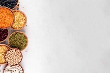 Çeşitli kuru fasulyeler, mercimek, mung, nohut, ahşap kaselerde bezelye çeşitleri. Legumes beyaz masa üst görünümünde. Vegan protein kaynakları yiyecek, kopyalama alanı