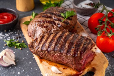 Ahşap kesme tahtasında ızgara biftek, ketçap sosu ve baharat, üst görünüm kopya alanı.