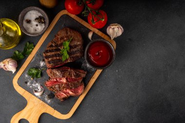 Ahşap kesme tahtasında ızgara biftek, ketçap sosu ve baharat, üst görünüm kopya alanı.