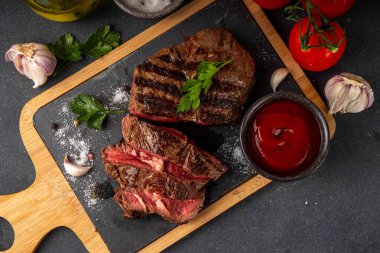 Ahşap kesme tahtasında ızgara biftek, ketçap sosu ve baharat, üst görünüm kopya alanı.