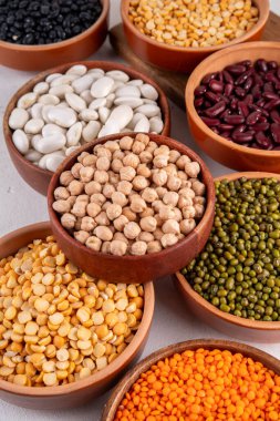 Çeşitli kuru fasulyeler, mercimek, mung, nohut, ahşap kaselerde bezelye çeşitleri. Legumes beyaz masa üst görünümünde. Vegan protein kaynakları yiyecek, kopyalama alanı