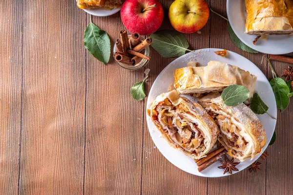 stock image Homemade fragrant autumn apple strudel with caramelized apples, raisins, nuts, honey, cinnamon spices, on plate on kitchen table copy space