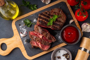 Ahşap kesme tahtasında ızgara biftek, ketçap sosu ve baharat, üst görünüm kopya alanı.