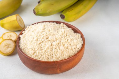 Alternatif organik muz unu taze taze ve dilimlenmiş yeşil muzlar beyaz masa arkasında.