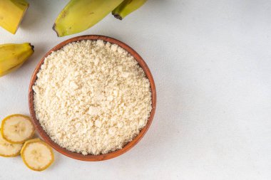 Alternatif organik muz unu taze taze ve dilimlenmiş yeşil muzlar beyaz masa arkasında.