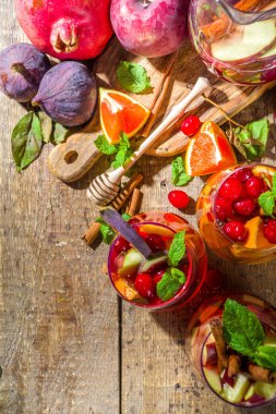 Geleneksel sonbahar kış içkisi sıcak baharatlı sangria - kırmızı, pembe, beyaz. Elma şarabı, pembe kırmızı şarap, elma, portakal, nar, kızılcık, erik, incir, tarçın çubukları. Ahşap kırsal tablo kopyalama uzayı