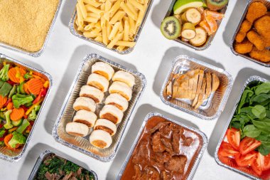 Yemek pişirme konsepti. Çeşitli çeşit mezeler: tahıl gevreği, makarna, makarna, pişmiş ve taze sebzeler, et, tavuk, nugget, kahvaltı krepleri ve yiyecek kabında meyve. 