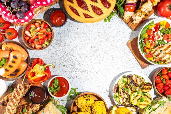 Çeşitli piknik barbekü yemekleri ve flatlay içiyorlar. Yaz bbq piknik yemekleri, ızgara etler, kebaplar, sebzeler, meyve salatası, geleneksel piknik pastası, sandviçler, üst görünüm fotokopi alanı.