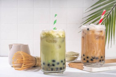 Klasik ve yeşil kibrit boba balonu çayı tapyoka incileri ve sütsüz krema bardağın üstünde, yaz aylarında tatlı tatlı içeceği beyaz masa arkasında fotokopi alanı