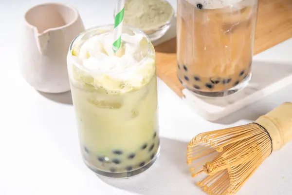 stock image Classic and green matcha boba bubble tea with tapioca pearls and whipped non-dairy creamer on top of glass, summer cold sweet dessert drink on white table background copy space