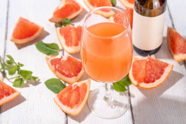 Greyfurt şarabı. Dilimlenmiş pembe greyfurt ve naneli şişe. Greyfurtlu narenciye şarabı.