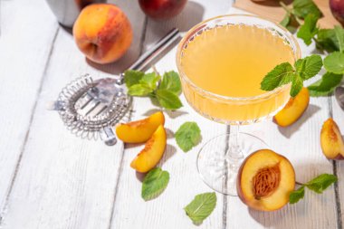 Şeftalili martini ya da margarita ya da limonata soğuk meyve suyu, nane ve limonlu yaz meyve suyu kokteyli, beyaz ahşap masa.