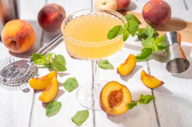 Şeftalili martini ya da margarita ya da limonata soğuk meyve suyu, nane ve limonlu yaz meyve suyu kokteyli, beyaz ahşap masa.