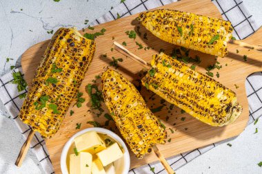 Sweet corn grilled with butter, cheese, cilantro and herbs. Vegetarian, healthy, clean eating barbeque food. Portioned bbq grill corn cobs on white background