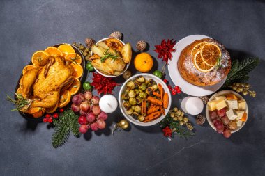 Noel ya da Yeni Yıl yemeği karanlık masada. Geleneksel Xmas parti yemekleri - pannetone, fırında tavuk, sebze, patates, peynir ve meyve tabağı, üst görünüm fotokopi alanı