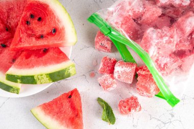 Donmuş karpuz dilimleri, donmuş poşetlerdeki taze çiğ karpuzlar mutfak masasındaki beyaz masa, sağlıklı basit konserve, kış konsepti için dondurulmuş meyve hasadı stokları.. 