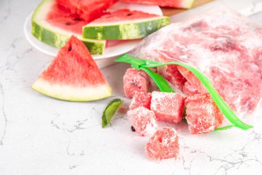 Donmuş karpuz dilimleri, donmuş poşetlerdeki taze çiğ karpuzlar mutfak masasındaki beyaz masa, sağlıklı basit konserve, kış konsepti için dondurulmuş meyve hasadı stokları.. 