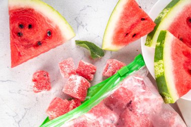 Donmuş karpuz dilimleri, donmuş poşetlerdeki taze çiğ karpuzlar mutfak masasındaki beyaz masa, sağlıklı basit konserve, kış konsepti için dondurulmuş meyve hasadı stokları.. 