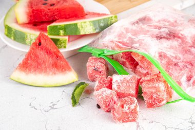 Donmuş karpuz dilimleri, donmuş poşetlerdeki taze çiğ karpuzlar mutfak masasındaki beyaz masa, sağlıklı basit konserve, kış konsepti için dondurulmuş meyve hasadı stokları.. 