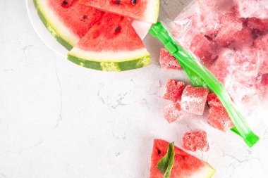 Donmuş karpuz dilimleri, donmuş poşetlerdeki taze çiğ karpuzlar mutfak masasındaki beyaz masa, sağlıklı basit konserve, kış konsepti için dondurulmuş meyve hasadı stokları.. 