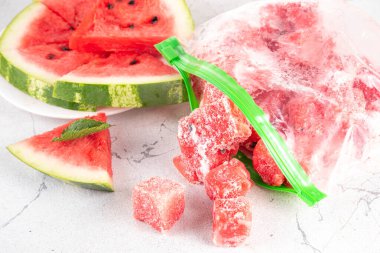 Donmuş karpuz dilimleri, donmuş poşetlerdeki taze çiğ karpuzlar mutfak masasındaki beyaz masa, sağlıklı basit konserve, kış konsepti için dondurulmuş meyve hasadı stokları.. 