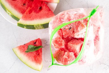 Donmuş karpuz dilimleri, donmuş poşetlerdeki taze çiğ karpuzlar mutfak masasındaki beyaz masa, sağlıklı basit konserve, kış konsepti için dondurulmuş meyve hasadı stokları.. 