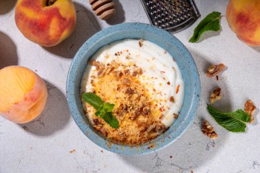 Dondurulmuş şeftali ve krema, kremalı ve yoğurtlu sağlıklı yaz atıştırması ve dondurulmuş şeftali meyveleri, fındık, bal ve nane, kopyalama alanı.