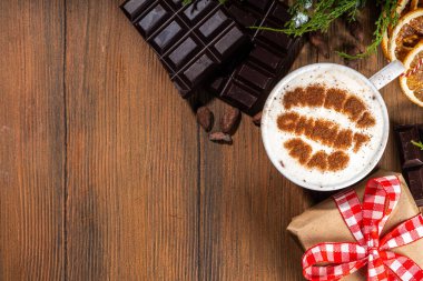 Cappuccino, sıcak çikolatalı latte kahve, mutlu noeller, sıcak ahşap arka planda çizimler, kadın ellerinde sıcak çikolata içeceği, üst düzey fotokopi alanı 