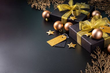 Mutlu Noeller, mutlu bayramlar tebrik kartı geçmişi, yeni yıl, Noel, kış xmas tatilleri düzlüğü. Noel altın süsleri, dekor köknar ağacı, siyah arkaplandaki hediye kutuları, fotokopi alanı