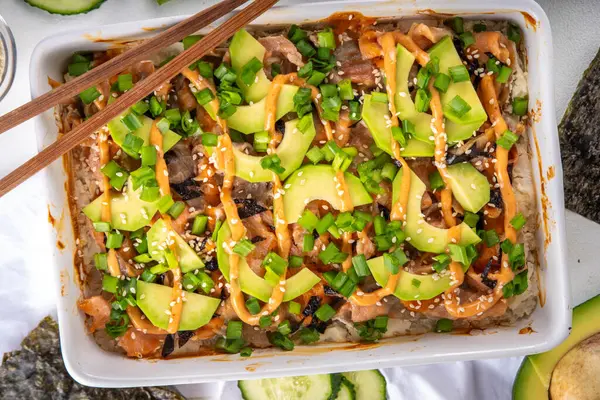 stock image Philadelphia Sushi Bake Recipe Casserole made with Rice, cream cheese, salmon trout, seaweed, avocado, sauce, green onion. Served with toasted nori sheets likea taco