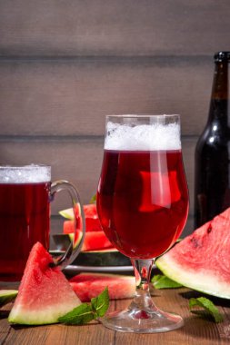 Glasses with tasty Sweet fruit berry watermelon Craft Beer, Cider or Ale on wooden table with fresh  watermelon slices clipart