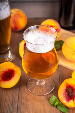 Ekşi meyveli bardaklar Şeftali Kaynağı Birası ya da ahşap masa üzerinde taze şeftali dilimli bira