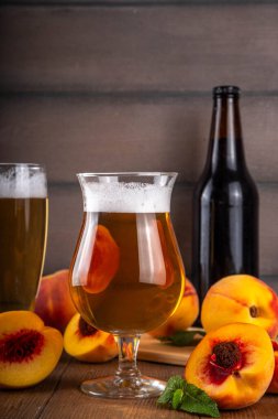 Ekşi meyveli bardaklar Şeftali Kaynağı Birası ya da ahşap masa üzerinde taze şeftali dilimli bira