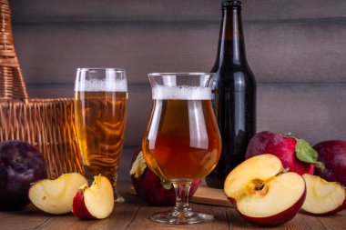 Ekşi elma suyu, elma suyu, elma şarabı veya bira ile dolu bardaklar taze kırmızı elma dilimleri ile ahşap masada.