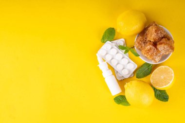 Soğuk algınlığı ve sonbahar mevsimi konsepti, geleneksel ve alternatif soğuk algınlığı ve grip tedavileri, haplar, akan burun, limon, bal ve parlak sarı arka planda nane şekeri için damlalar.