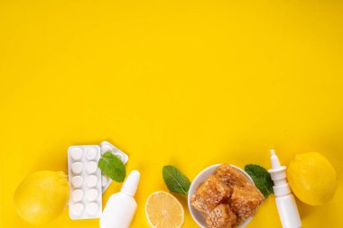 Soğuk algınlığı ve sonbahar mevsimi konsepti, geleneksel ve alternatif soğuk algınlığı ve grip tedavileri, haplar, akan burun, limon, bal ve parlak sarı arka planda nane şekeri için damlalar.