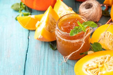 Altın kabak reçeli. Tatlı balkabağı ve portakal reçeli ya da küçük kavanozda dilimlenmiş balkabağı ve nane ile ahşap mutfak masasında bulunan konfeksiyon.