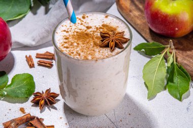 Apple pie smoothie with yogurt, apple slices, oatmeal granola flakes, cinnamon, spices and walnuts. Healthy uatumn breakfast or snack, with fresh raw apples and spices copy space